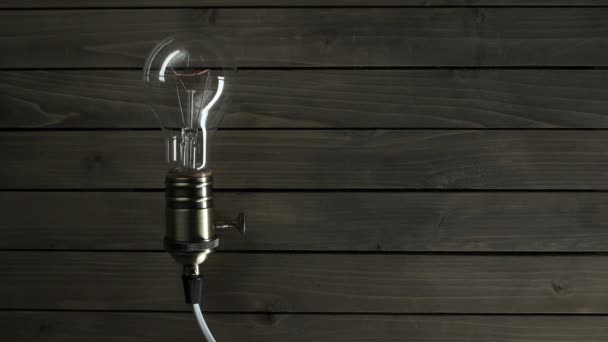 Žárovka svítí na dřevěné pozadí — Stock video