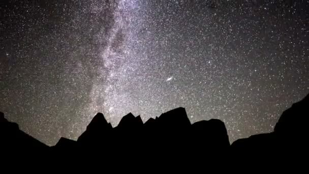 Timelapse of moving star trails in night sky (en inglés). La galaxia de la Vía Láctea girando sobre la cordillera en verano — Vídeos de Stock