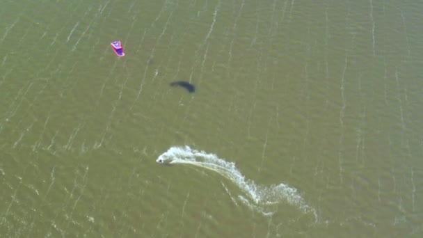 Vista aérea de kitesurfer deslizándose y saltando a través del océano — Vídeos de Stock