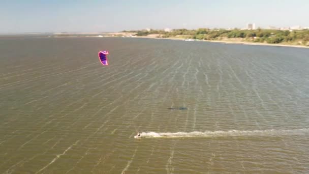 Vista aérea de kitesurfer deslizándose y saltando a través del océano — Vídeos de Stock