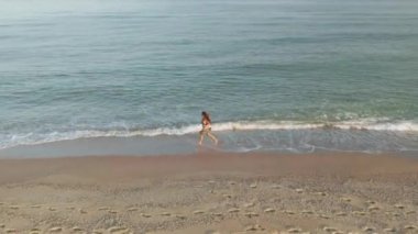 ince sportif kadın deniz kıyısında sabahın erken saatlerinde tek başına çalışıyor