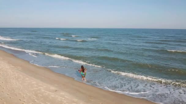 Сцена с женщиной, гуляющей по океанскому пляжу на закате — стоковое видео