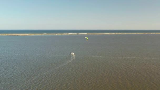 Vista aérea de kitesurfer deslizando e pulando através do oceano — Vídeo de Stock