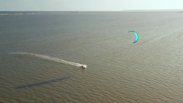 Vista aérea de kitesurfer deslizando e pulando através do oceano — Vídeo de Stock