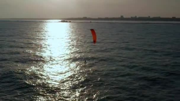 Vista aérea de kitesurfer deslizándose y saltando a través del océano — Vídeos de Stock