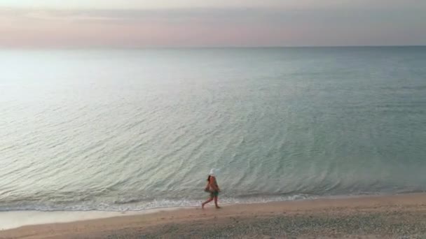 Όμορφη σκηνή μιας γυναίκας που περπατάει στην παραλία του ωκεανού το ηλιοβασίλεμα. Χαρούμενο ευτυχισμένο κορίτσι χαλάρωσης δείχνοντας χαρά και ευτυχία σε λεπτό σώμα για δίαιτα απώλειας βάρους έννοια. Αεροφωτογραφία. — Αρχείο Βίντεο