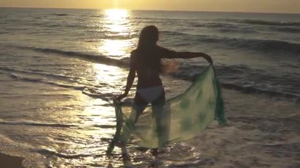 Mujer joven delgada está bailando en la playa al atardecer . — Vídeos de Stock