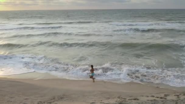 Szczupła sportowa kobieta działa sam wcześnie rano na wybrzeżu. Wschód słońca — Wideo stockowe