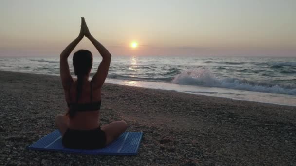 Bella giovane donna che fa Yoga seduto sulla spiaggia mentre guarda il tramonto . — Video Stock