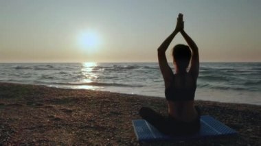 Güzel Genç Kadın Sahilde Gün Batımını izlerken Oturan Yoga Yapıyor.