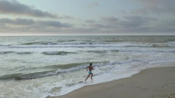 Femme faisant du jogging sur la plage au coucher du soleil. Beaux nuages et coucher de soleil à couper le souffle . — Video