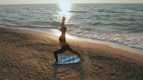 Girl doing yoga exercises near the stormy sea. Slow motion. Sunrise background — Stock Video