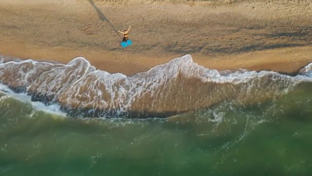 Meisje doet yoga oefeningen bij de stormachtige zee. Langzame beweging. Zonsopkomst achtergrond — Stockvideo