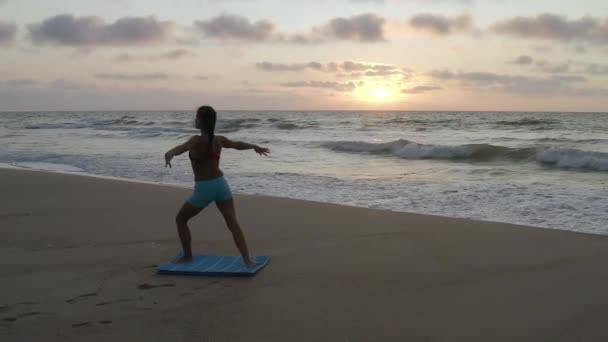 Girl doing yoga exercises near the stormy sea. Slow motion. Sunrise background — Stock Video