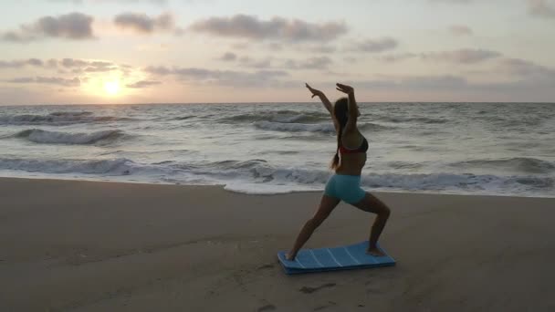 Dívka cvičí jógu u bouřlivého moře. Zpomal. Pozadí východu slunce — Stock video