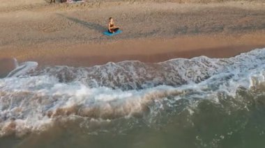 Güzel Genç Kadın Sahilde Gün Batımını izlerken Oturan Yoga Yapıyor.