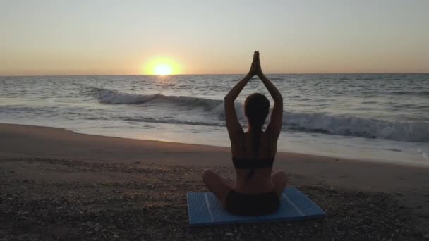 Vacker ung kvinna som gör sittande yoga på stranden medan du tittar på solnedgången. — Stockvideo