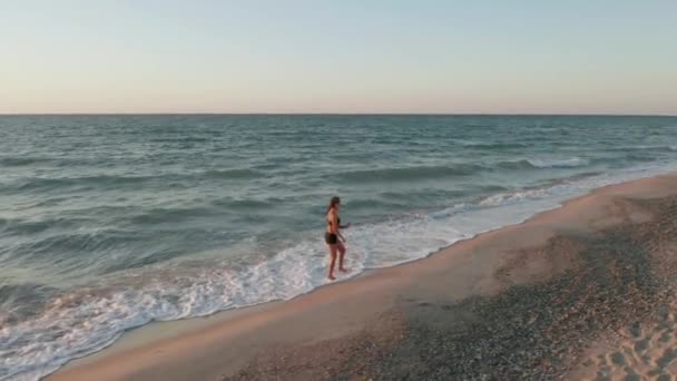 Femme court seule tôt le matin sur le littoral. Lever de soleil — Video