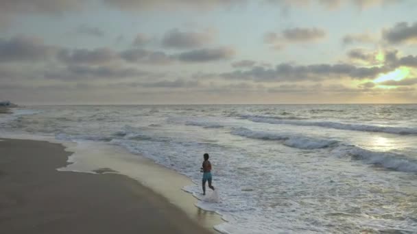 Η γυναίκα τρέχει μόνη της νωρίς το πρωί στη θάλασσα. Ανατολή ηλίου — Αρχείο Βίντεο
