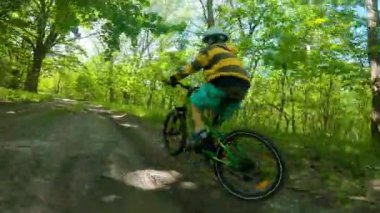 Bir çocuk ormanda bir yolda bisiklete biniyor. Bahar parkındaki yol. Çocuk sporu.