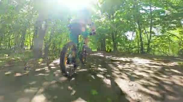 Мальчик едет на велосипеде по тропинке в лесу. Дорога в весеннем парке. Детский спорт . — стоковое видео
