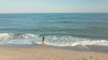 Güzel, genç bir kız okyanus boyunca yürüyor.