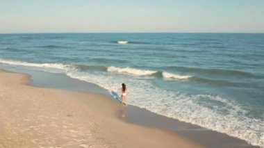 Güzel, genç bir kız okyanus boyunca yürüyor.