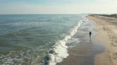 Güzel, genç bir kız okyanus boyunca yürüyor.