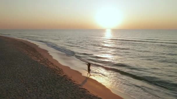 Une belle jeune fille se promène le long de l'océan au lever du soleil — Video