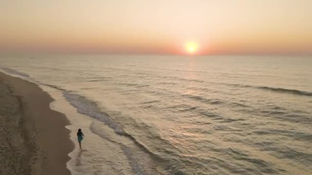 Una hermosa joven camina a lo largo del océano al amanecer — Vídeos de Stock