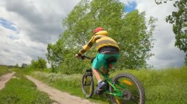 Bir çocuk ormanda bir yolda bisiklete biniyor. Bahar parkındaki yol..