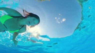 Sualtı çatışması. Kız mavi yüzme havuzunda yüzüyor.