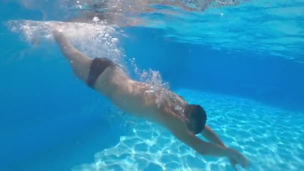 Fusillade sous-marine. Homme plonger dans la piscine bleue. — Video