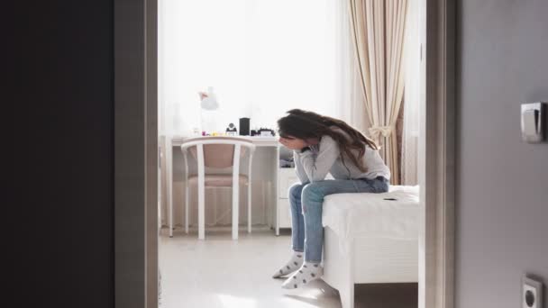 Sad child sitting on bed close her face with hands — Stock Video