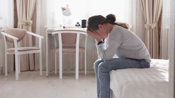 Verdrietig meisje zittend op bed haar gezicht met handen dicht — Stockvideo