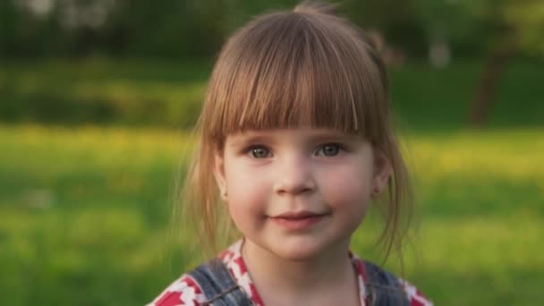 Радостная маленькая девочка смотрит в камеру и улыбается — стоковое видео