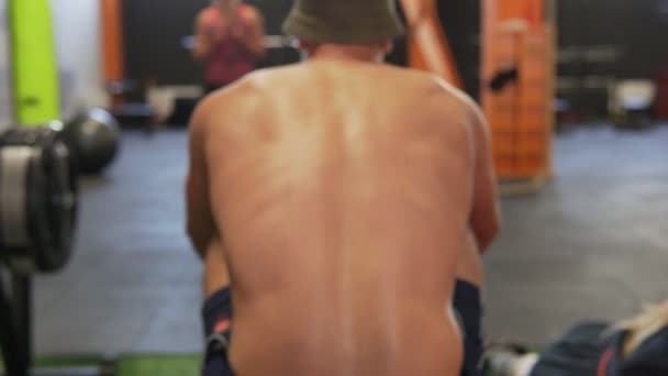 Γυμναστήριο άνθρωπος κάνει κωπηλασίας προπόνηση στο γυμναστήριο, ΠΙΣΩ ΟΨΗ — Αρχείο Βίντεο