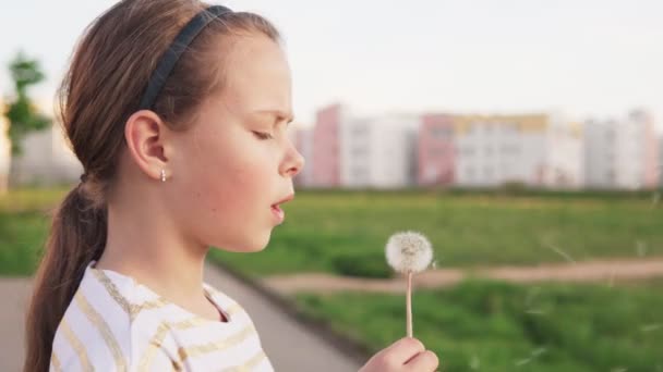 Carino bambina che soffia sul dente di leone sul prato della città — Video Stock