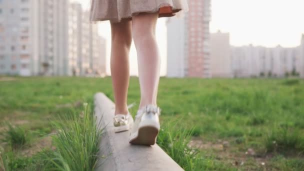 Jambes de petite fille marchant sur la bûche de béton sur la pelouse urbaine — Video