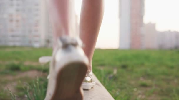 Nahaufnahme der Beine eines kleinen Mädchens, das auf einem Betonklotz auf der Ödnis der Stadt läuft — Stockvideo