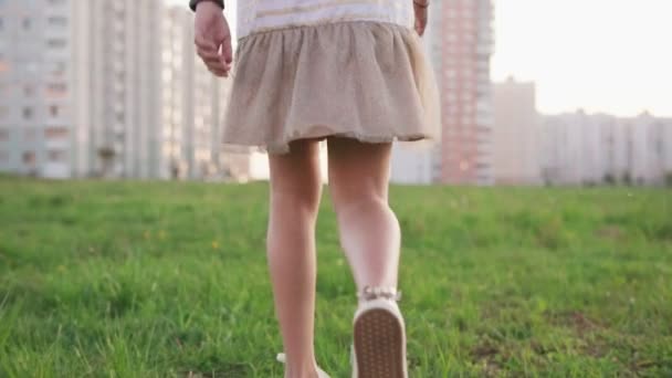 Маленькая девочка бегает по траве на городской лужайке в летний день — стоковое видео