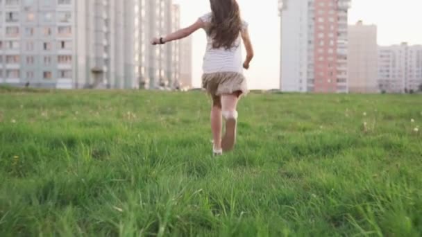 Niña corriendo sobre hierba en un páramo urbano — Vídeos de Stock