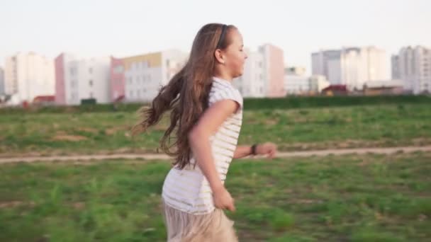 Graciosa niña corriendo sobre hierba en el césped de la ciudad en el día de verano — Vídeos de Stock