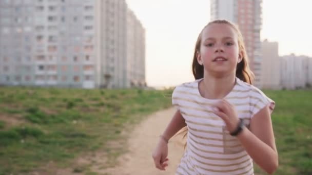 Милая маленькая девочка, бегущая против городской пустоши — стоковое видео
