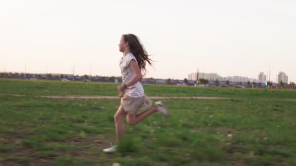 Bonne petite fille courir sur l'herbe sur la pelouse de la ville dans la journée d'été — Video