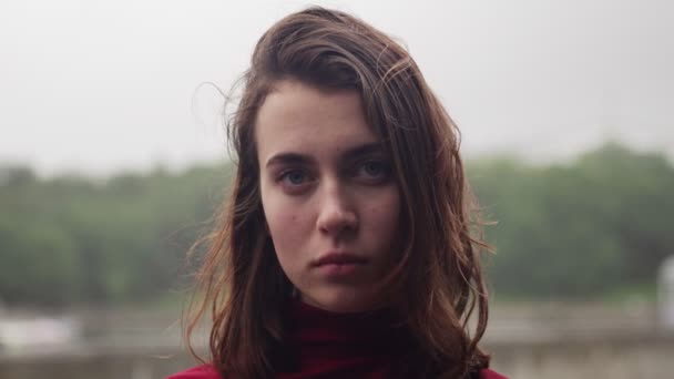 Face of young woman with sad look and wet hair in rain, cloudy bad weather — Stock Video