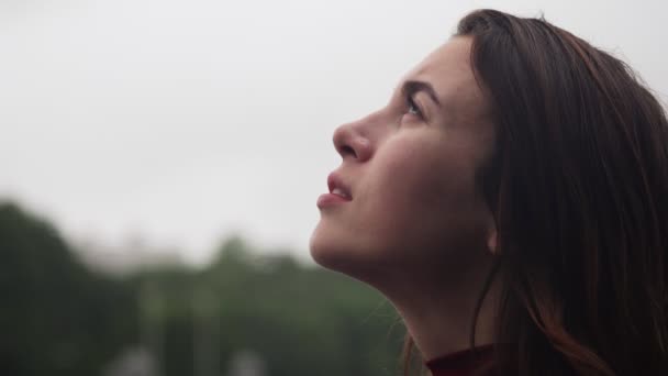 Närbild ansikte av ung sensuell kvinna som tittar upp på regn — Stockvideo