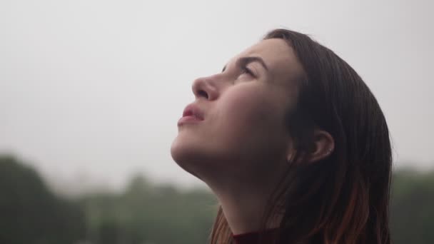 Joven mujer triste con el pelo mojado mira a la lluvia con esperanza, mal tiempo nublado — Vídeos de Stock