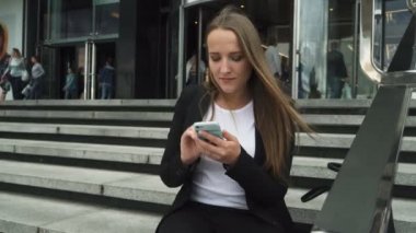 İş kadın kentsel yapı ve smartphone kullanarak basamaklarında oturuyordu