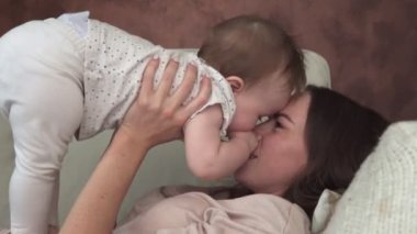 Mutlu anne gülümseyerek ve bebek öpüşme koltukta yalan